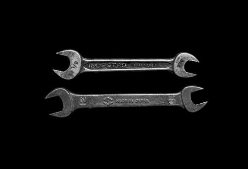 Two silver wrenches are positioned horizontally against a black background. The upper wrench has the inscription 'INDESTRO CHICAGO U.S.A.' with measurements indicated as '1/2'. The lower wrench is labeled 'MADE IN JAPAN' with measurements marked as '12' and '10'.