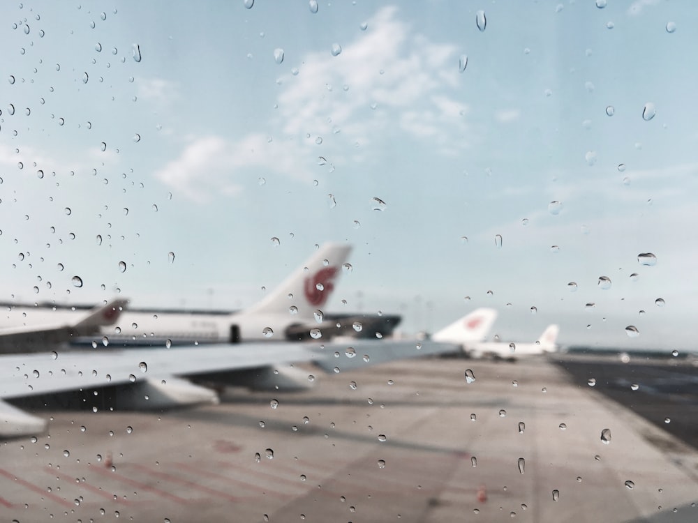 雨に濡れたカメラで撮影された空港の飛行機。