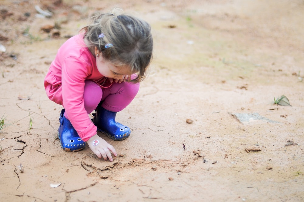 Ein kleines Mädchen spielt im Sand.
