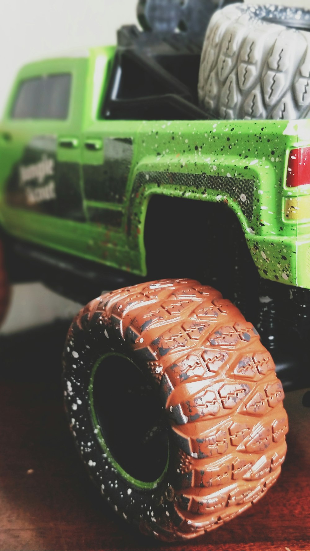 Large dirty tires on a green toy truck.