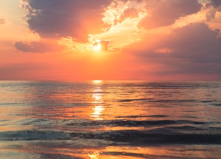 sea under white clouds at golden hour