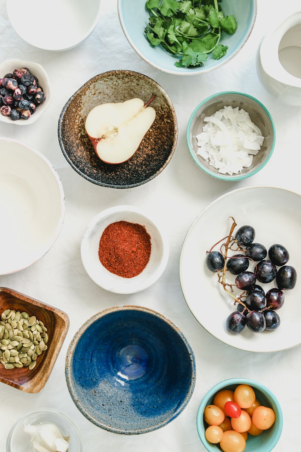 An overhead shot of fruits, seeds and spices in bowls