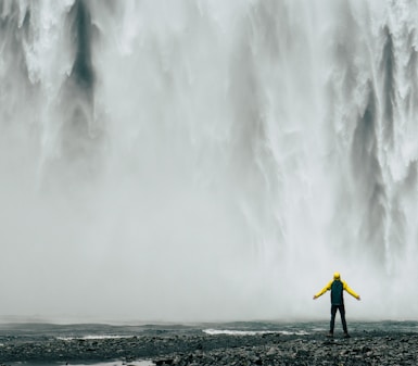 man standing in front of waterfalls at daytime