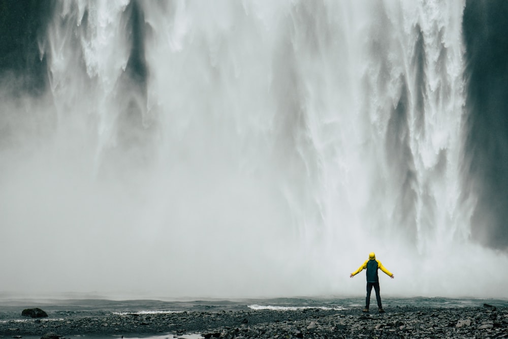 homem em pé na frente de cachoeiras durante o dia