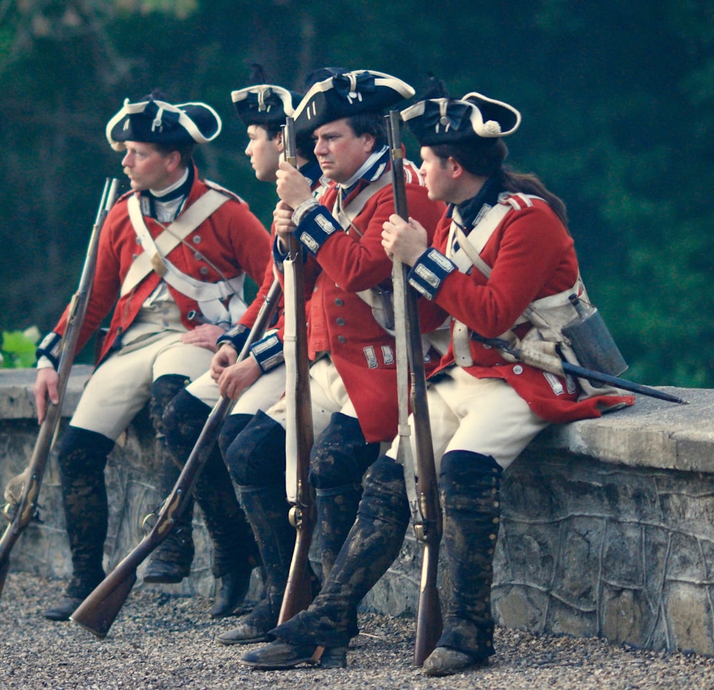 four men in uniforms holding rifles