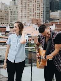 man playing guitar beside singing woman