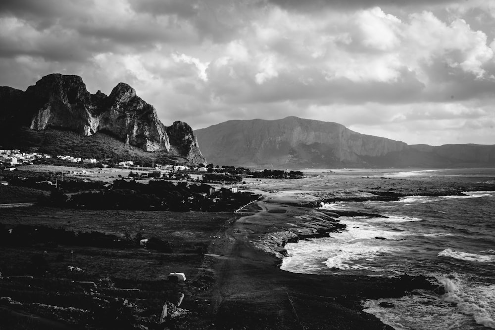 a black and white photo of a beach with mountains in the background