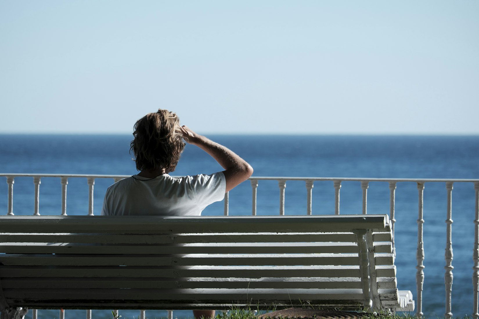 A solo traveller sitting on a bench by the water, taking quiet time alone