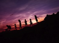A sunset silhouette of children playing soccer on a dusty field, laughter in the air.