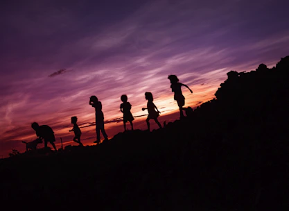 Children happily playing on colorful bouncy castles under a glowing sunset sky.