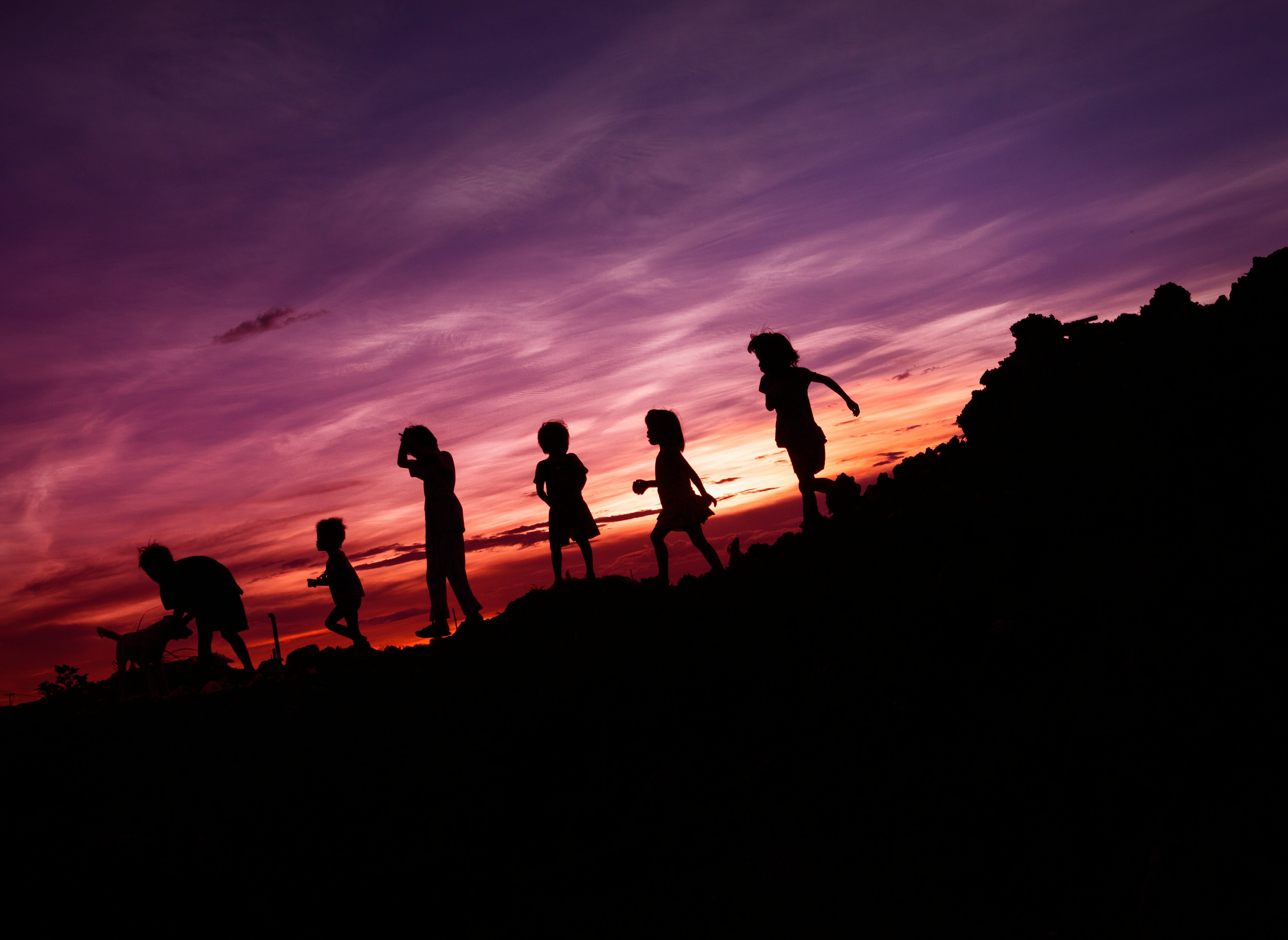 Stock photo of children silhouetted against a sunset sky