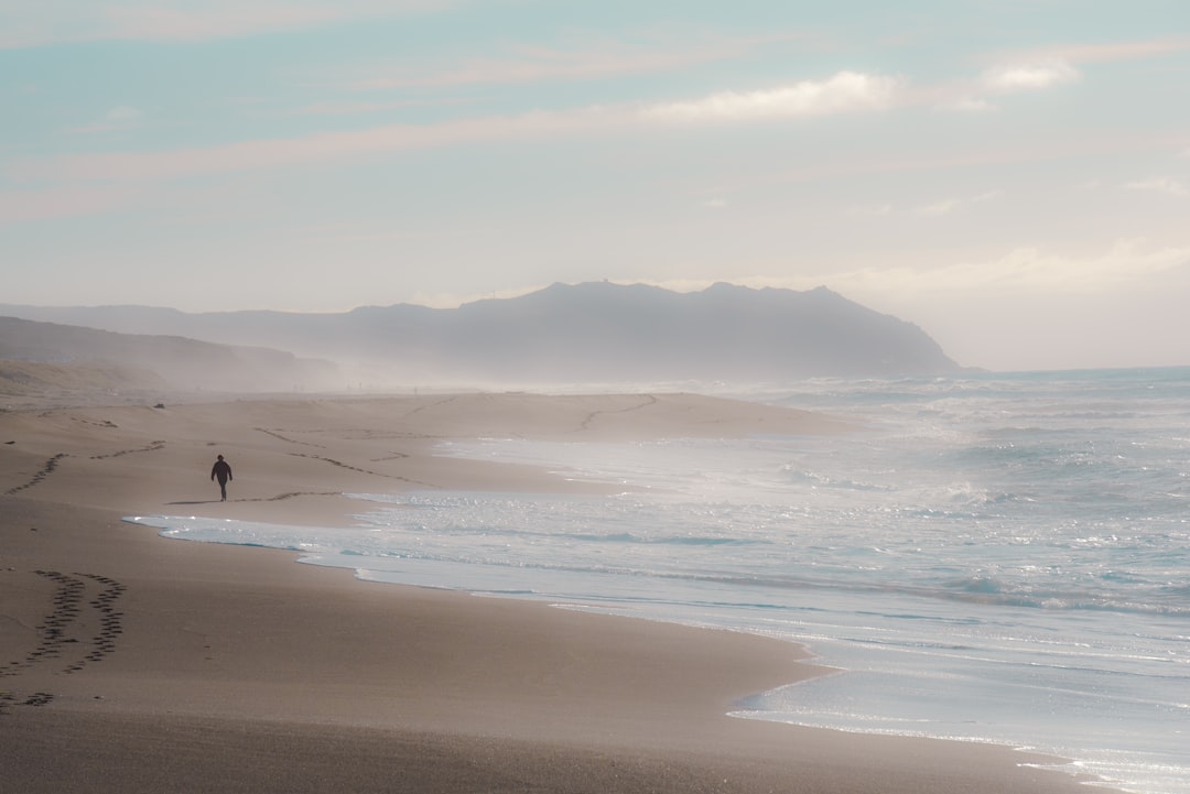 man walking beside body of water