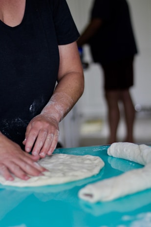 A smiling baker shaping dough in the rustic bakery kitchen.