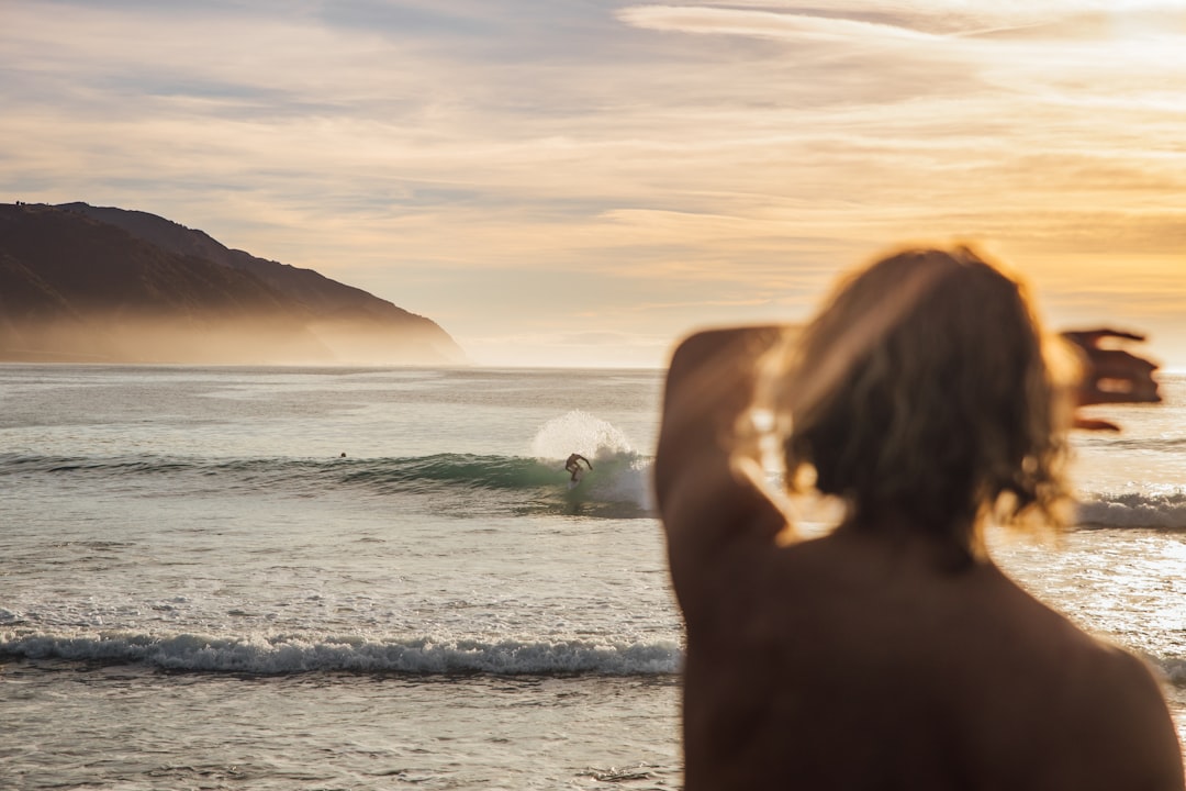 person covering eyes in front of body of water