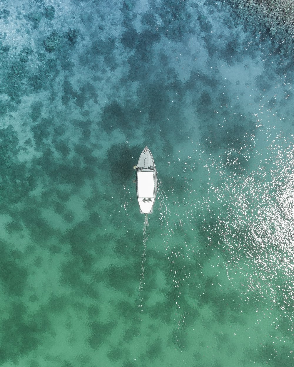 Photo à vol d’oiseau d’un bateau blanc sur un plan d’eau pendant la journée