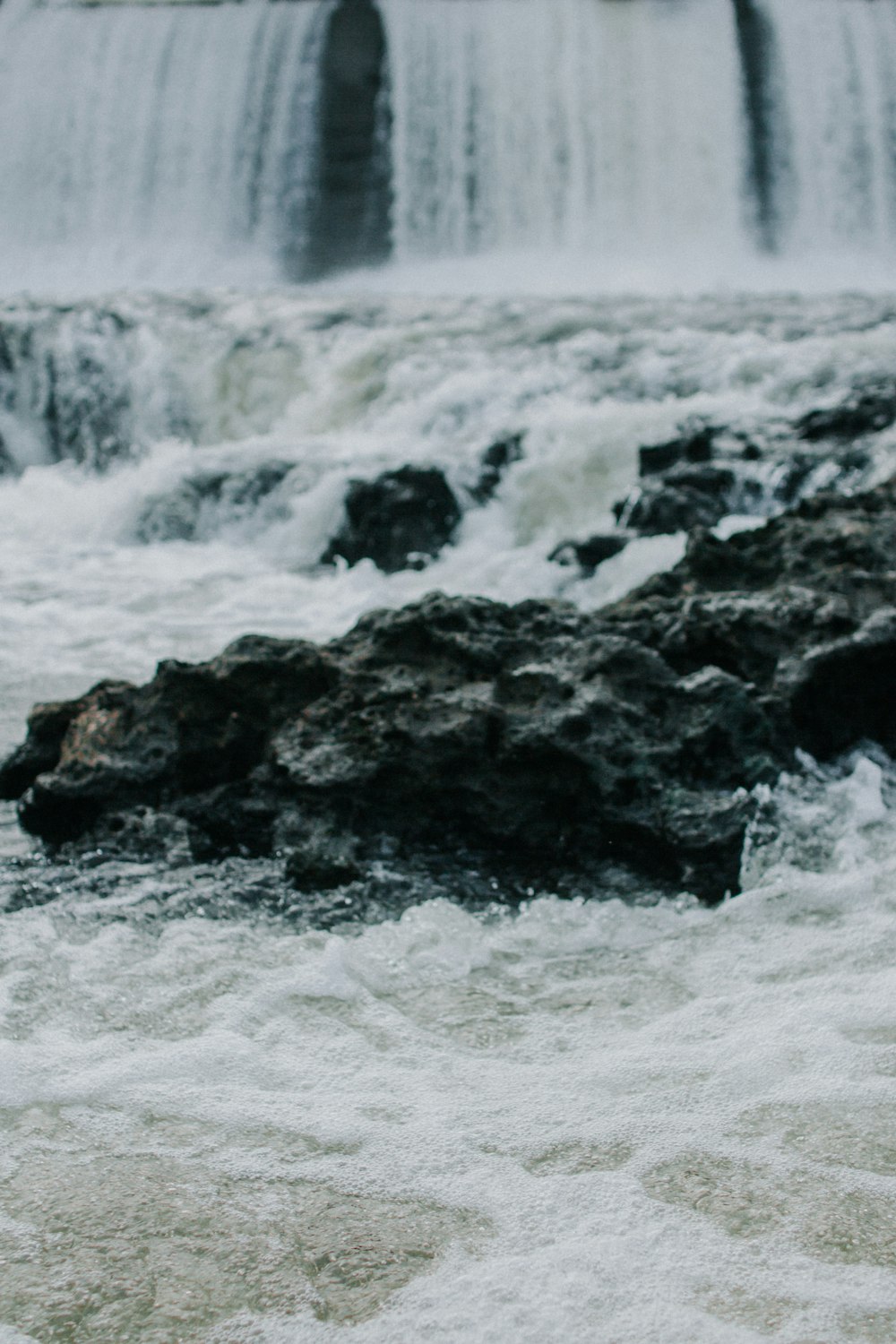 selective focus photography of black rock in waterfalls at daytime