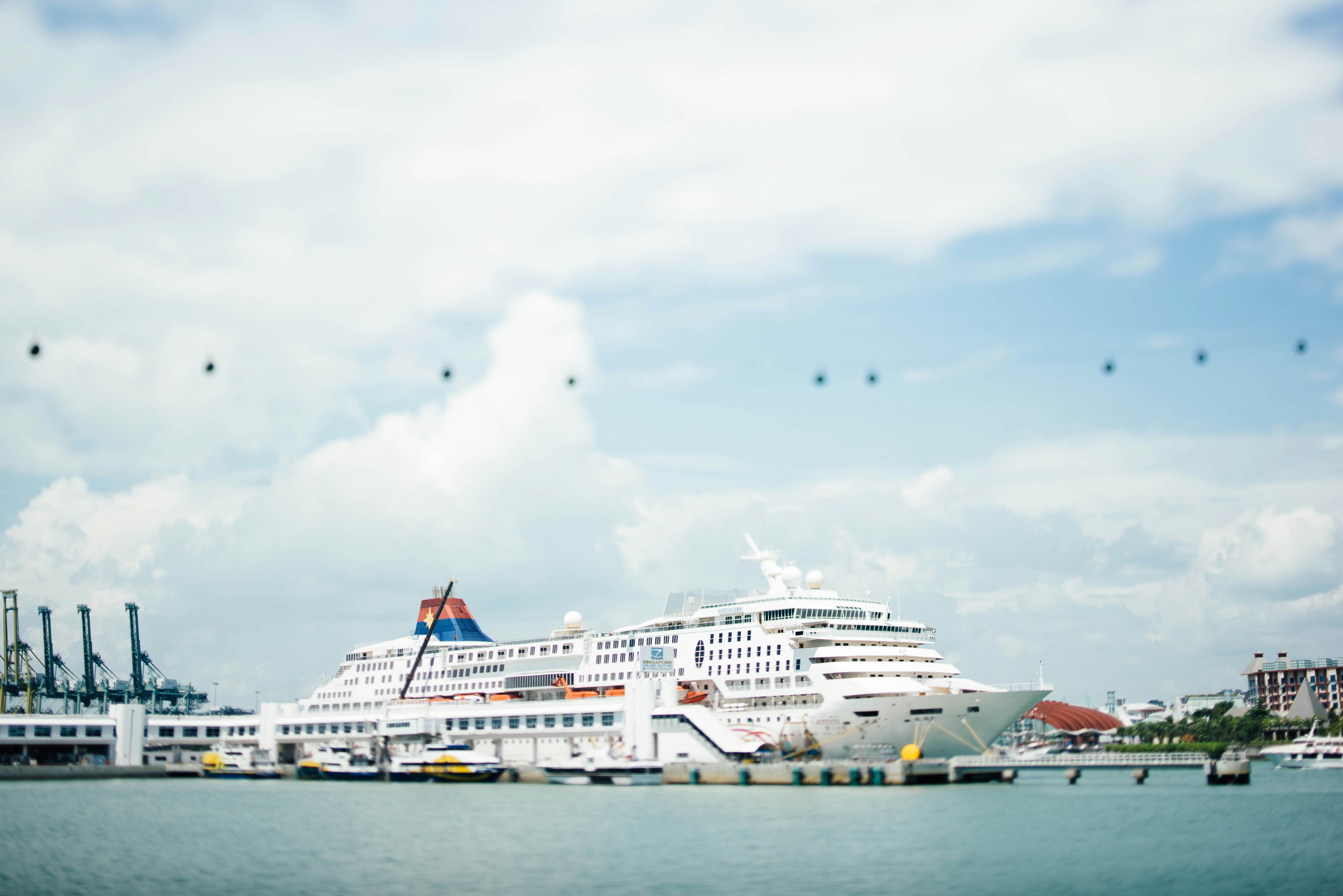 white cruise ship docking on blue bod of water under blue sky, 