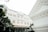 A grand colonial-style hotel with an ornate facade and arched windows is surrounded by lush greenery. The architecture features intricate details and a classic design, giving it an elegant appearance.