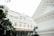 A grand colonial-style hotel with an ornate facade and arched windows is surrounded by lush greenery. The architecture features intricate details and a classic design, giving it an elegant appearance.