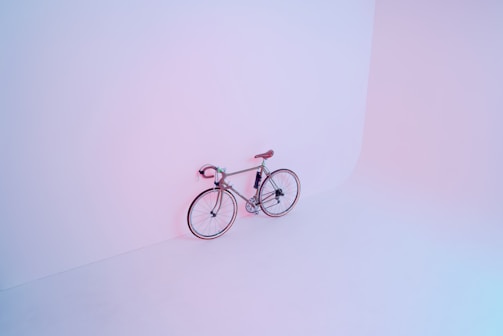 Finished bicycle leaning against a white wall, showcasing minimalist design.