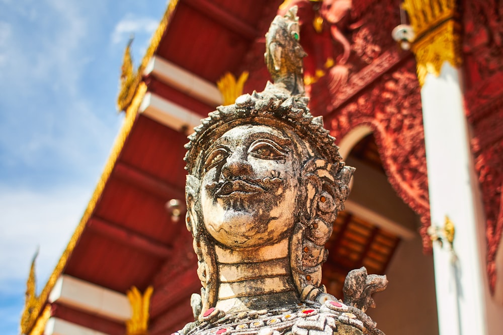 brown concrete statue under red and white roof