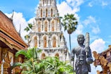 religious figurine near gray concrete mosque under blue and white cloudy sky