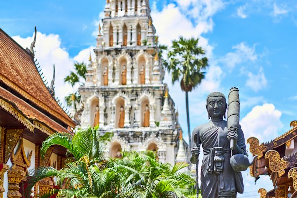 Religious figurine near gray concrete mosque under blue and white cloudy sky — Pai, Thailand