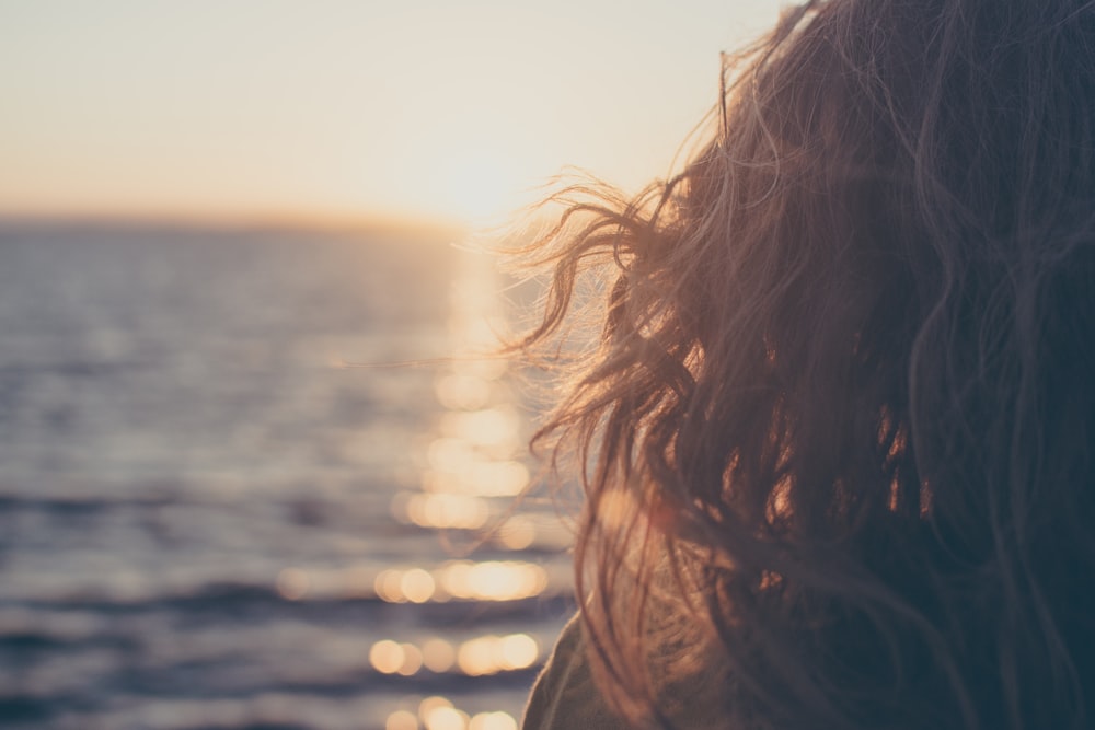 woman standing near body of water during golden hour