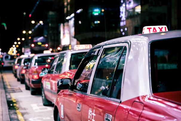 A modern fleet of diverse taxis lined up under city lights in Kuwait.