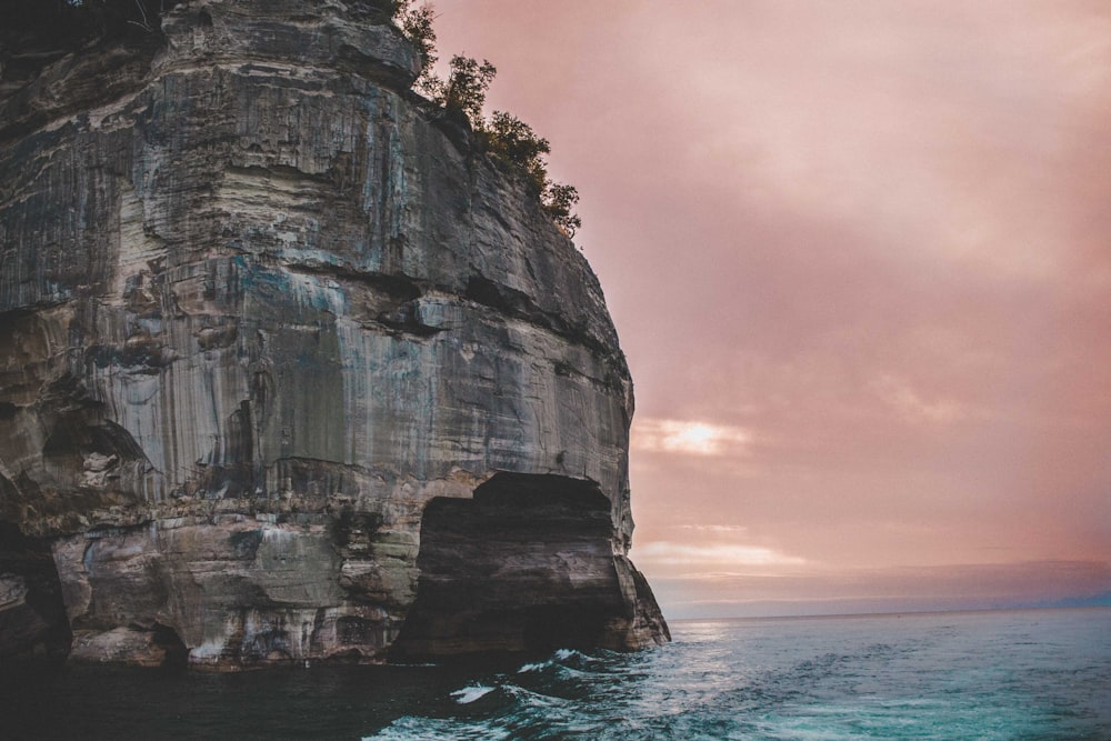 gray rock formation at the sea with silhouette of trees