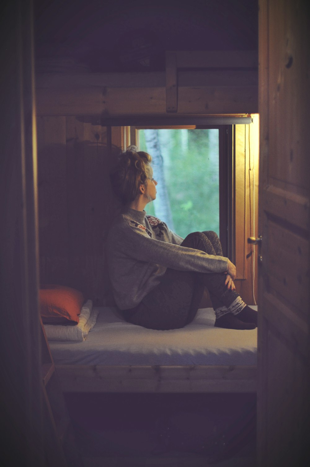 A sad female sitting with her knees up in bed.