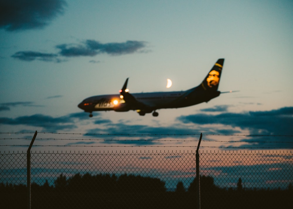 Foto de un avión comercial negro listo para aterrizar durante la hora dorada