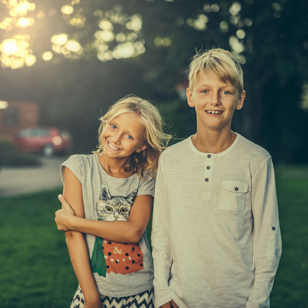 girl and boy standing on green grass field