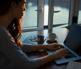 woman sitting beside table using laptop