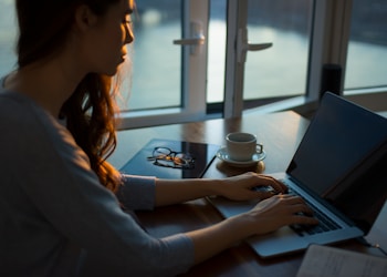 woman sitting beside table using laptop