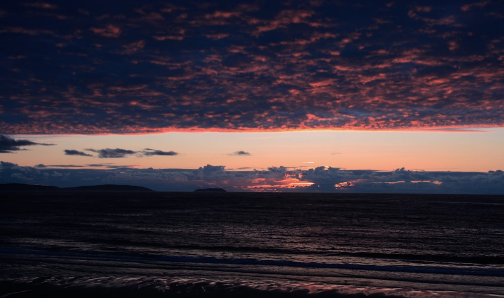 A purple cloud covered sky above a beach.