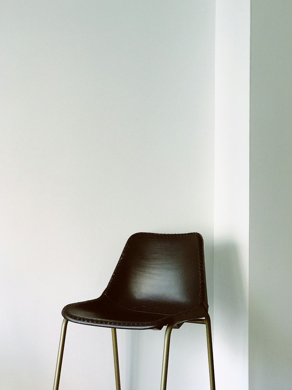 sedia marrone vicino al muro dipinto di bianco