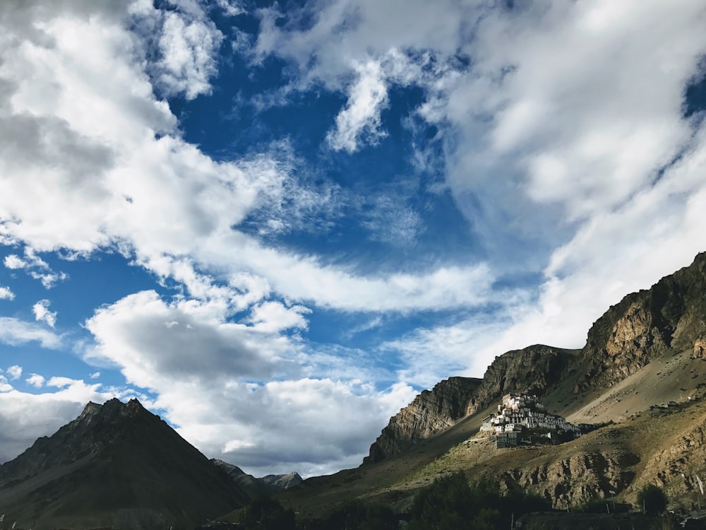 Montanhas verdes e marrons sob céu azul e nuvens brancas durante o dia