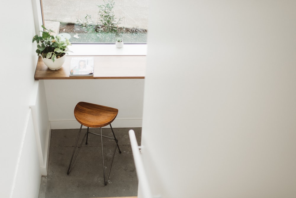 brown stool below brown tabletop with green plant in white pot