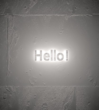 A textured wall with a luminous sign displaying the word 'Hello!' in bright white letters, casting a soft glow around it.