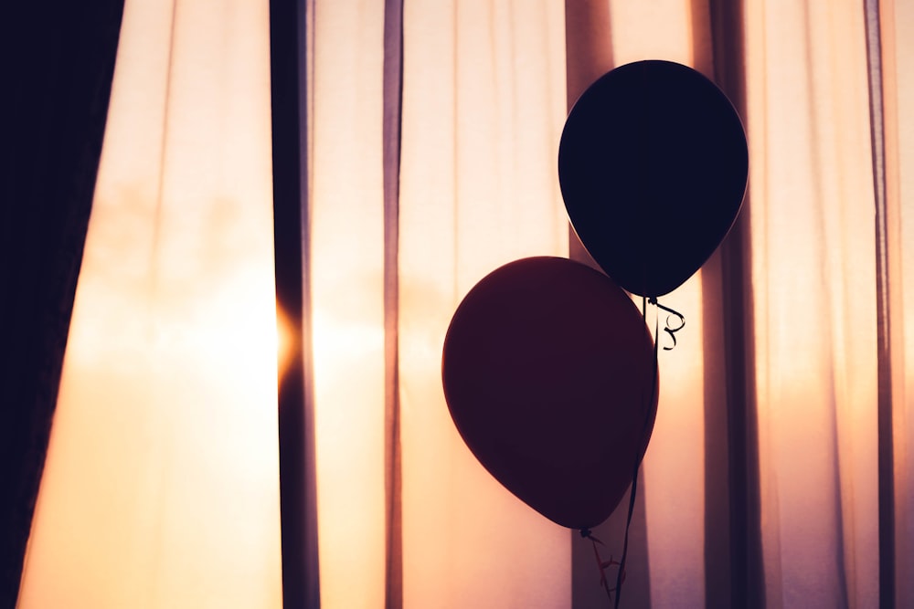 two balloons near brown curtain