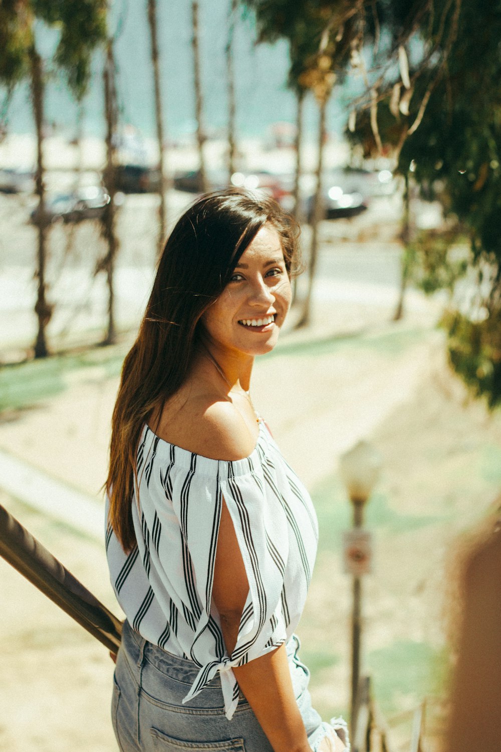 smiling woman standing beside handrails during daytime