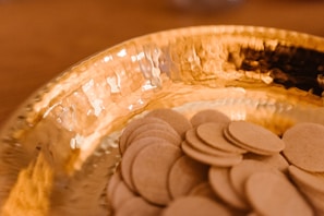 Close-up of golden amaranto obleas stacked on a rustic wooden table with natural light highlighting their texture