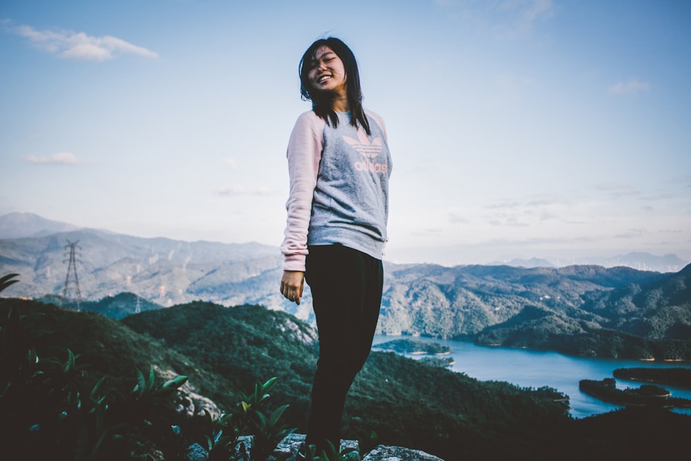 woman standing at the peak of mountain