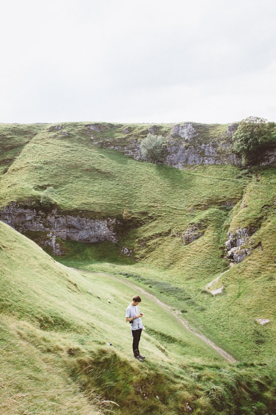 man standing on green grass on mountain in Cave Dale United Kingdom