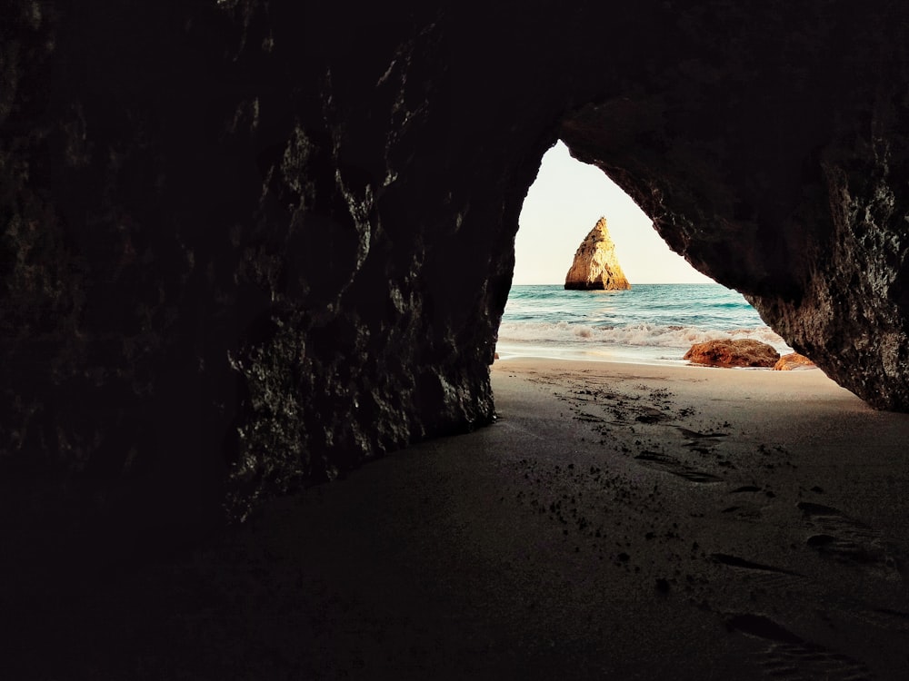 Caverna marrom perto do corpo de água durante o dia