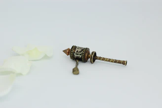 Close-up of a hand gently holding a Tibetan prayer wheel against a white background.