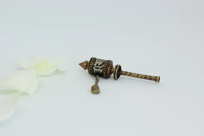 Close-up of a hand gently holding a Tibetan prayer wheel against a white background.