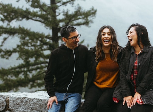 man sitting beside two woman on gray surface