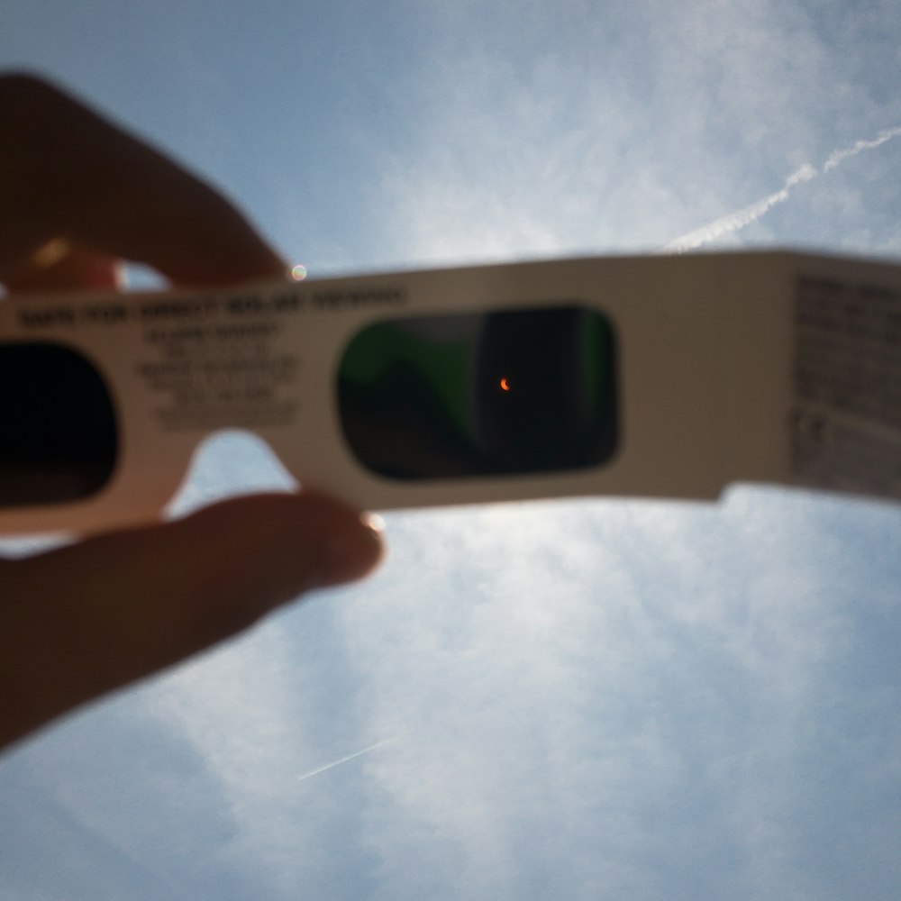 person's hand holding white 3D sunglasses